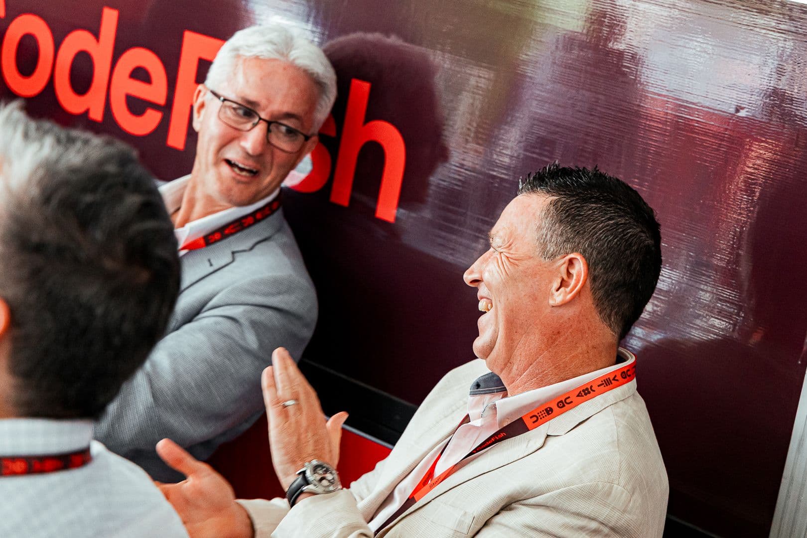 Three guests in conversation and laughing in front of a large CodeFish backdrop