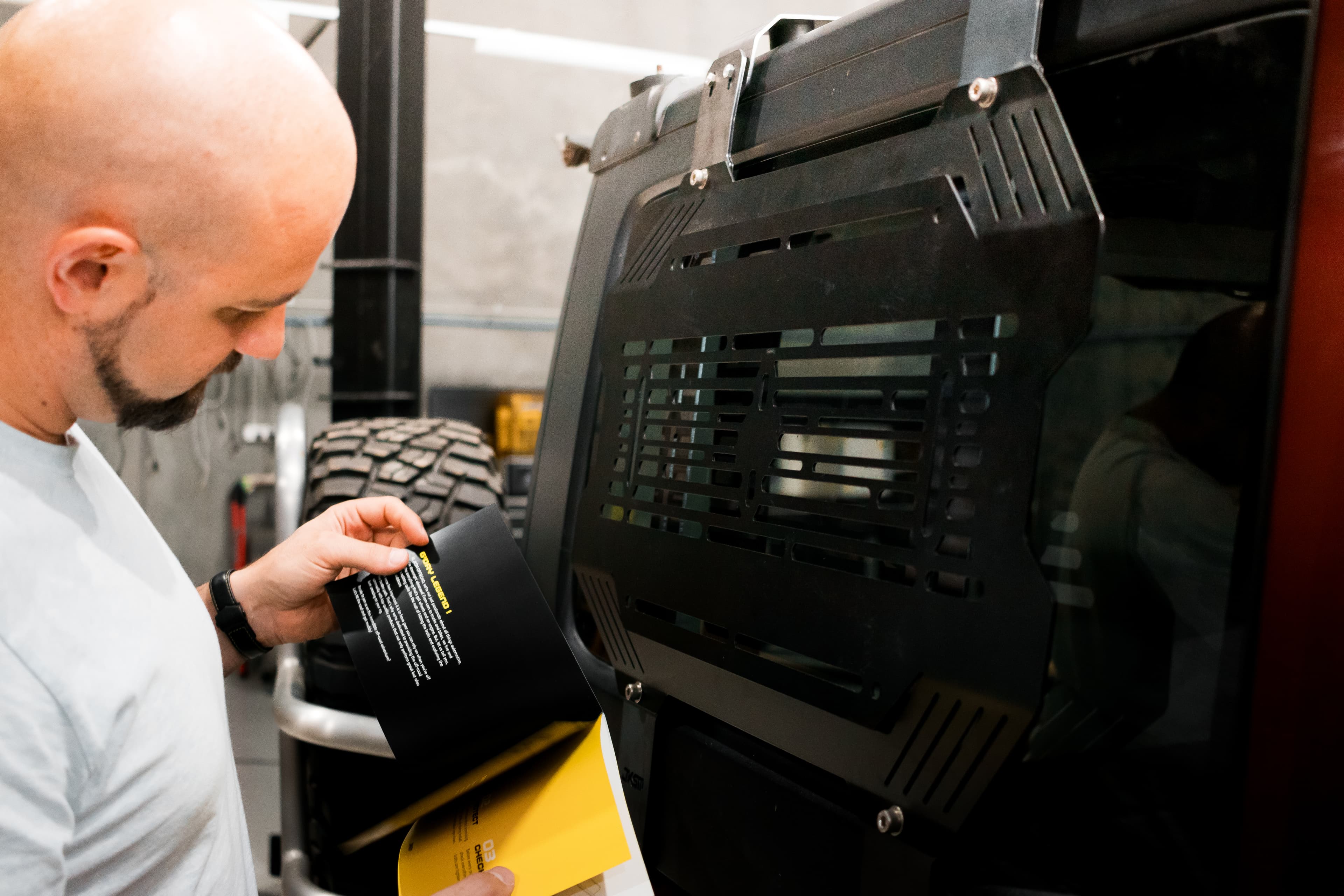 A team member reviewing printed documents beside a black storage panel fitted to a vehicle window