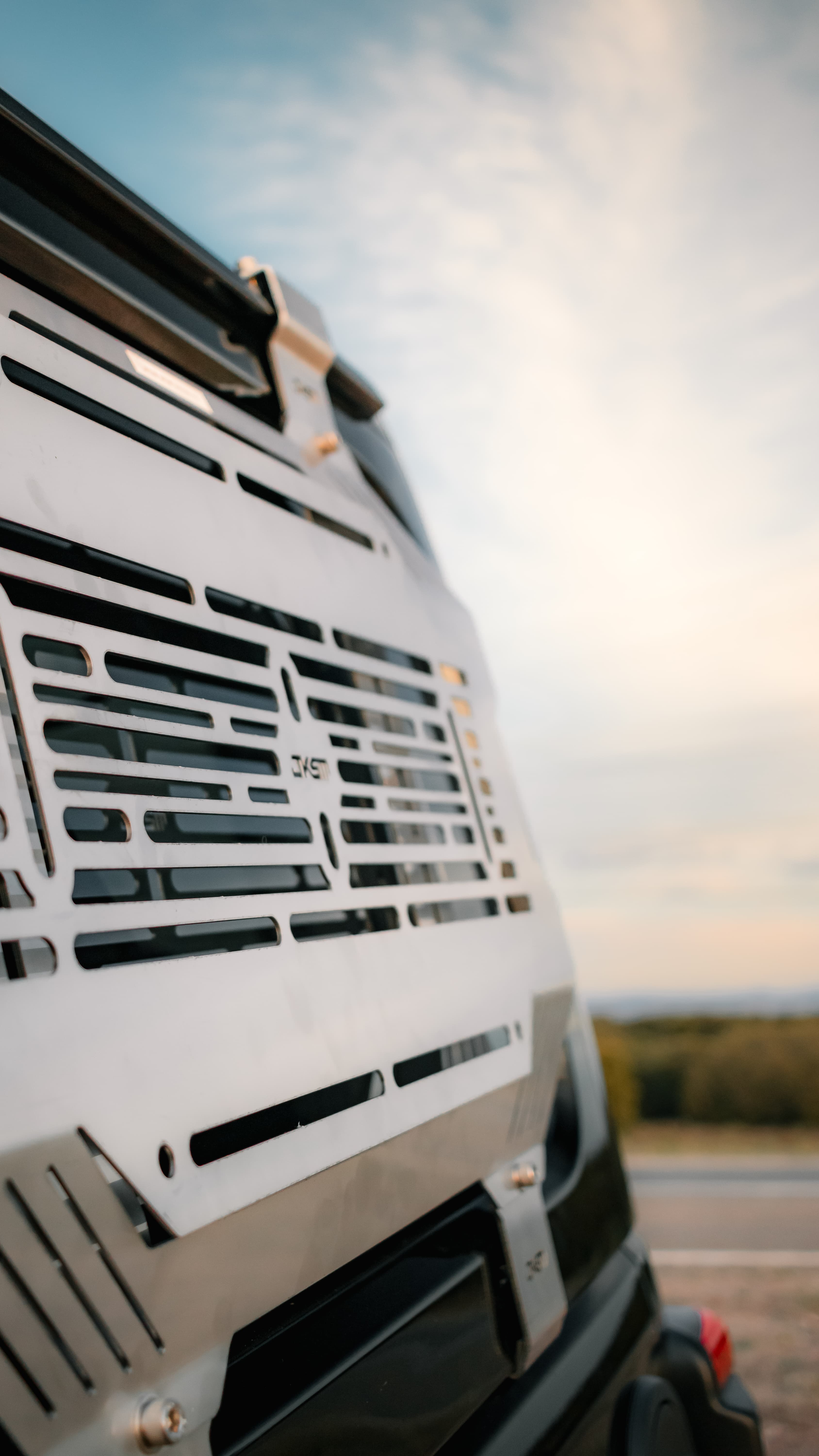 Slotted alloy storage panel on a vehicle window, shot low against an open sky
